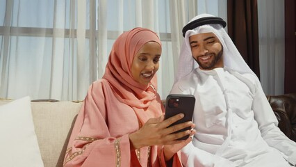 Wall Mural - Happy couple wearing traditional clothes from the emirates spending time in their beautiful apartment in Dubai