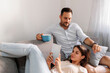 © Impact Photography - Couple drinking coffee and using tablet computer while relaxing at home