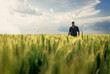 © Zoran Zeremski - Portrait of young farmer walking in a green wheat field at sunset.