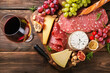 Assorted cold cuts with ham, salami, cheese, and wine.