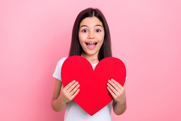 Wall Mural - Photo portrait of pretty young child girl hold red heart figure shock dressed stylish white clothes isolated on pink color background