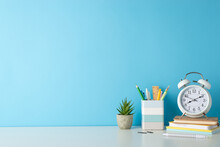 Promote A Productive Study Environment With Side-angle Photo Featuring White Desk, Alarm Clock, Notepads, Penholder, And Office Supplies On Blue Backdrop, Providing Ample Copy-space For Text Or Ads