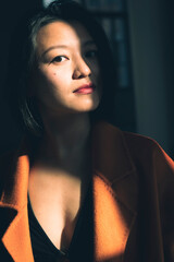 Portrait of a thoughtful young Chinese woman wearing a beautiful orange coat