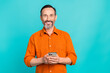 © deagreez - Photo of pleasant cheerful toothy beaming man with white gray beard wear stylish shirt hold smartphone isolated on teal color background