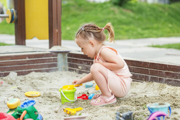 Little girl playing in sandbox at playground outdoors. Toddler playing with sand molds.