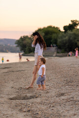 Wall Mural - Mother and baby boy holding hands and walking down the beach