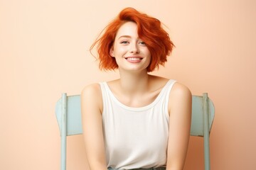 Wall Mural - Beautiful young fictional ginger woman model sitting on a chair and smiling. Isolated on a plain pastel colored background. Generative AI.