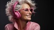 © mariiaplo - Happy mature woman with grey hair and pink headphones in bright eyeglasses.