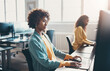 © Flamingo Images - Young businesswoman and colleagues sitting at office desks and working on computers