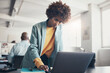 © Flamingo Images - Young businesswoman working on a laptop with coworkers sitting in the background