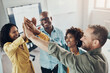 © Flamingo Images - Diverse team of laughing businesspeople standing with their hands raised together