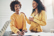 © Flamingo Images - Two businesswomen laughing while working together at an office table