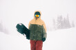 © Annatamila - Portrait of snowboarder with board wearing mask in snowy winter landscape outdoors