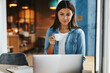 © Flamingo Images - Smiling young female entrepreneur drinking coffee and using a laptop