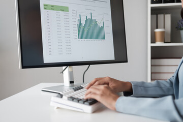 Poster - Close up view of young businesswoman typing on keyboard computer while analyzing graph and trend in her office room.