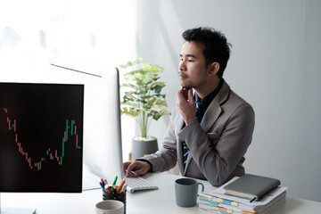 Aufkleber - Middle aged Asian businessman analyzing investment trending, working on the computer in his office room.