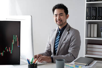 Aufkleber - Middle aged Asian businessman analyzing investment trending, working on the computer in his office room.