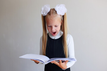 Surprised school girl look into the open book 