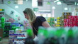 © Marco - Female consumer browsing products at supermarket. Person pondering buying decision inspecting items by drink soda sector