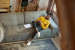 © master1305 - Top view image of young african man in yellow sweater, sitting on sofa in living room at home and watching videos on tablet. Concept of business and education, freelance job, modern lifestyle
