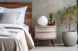 Cozy pastel colored bedroom interior in with a wooden bedside table and a plant on it