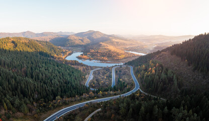 Canvas Print - Autumn mountains panorama with mountain road serpentine, river and mixed forest. Aerial drone view. Landscape photography