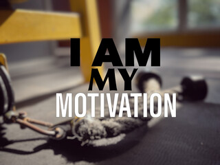 Wall Mural - Motivational and inspirational wording. Health and fitness concept. I Am My Motivation written on blurred background of gym equipment.