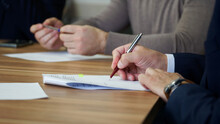 A Man Signs A Document During A Business Meeting Or Negotiations. Signing An Order, Deal, Memorandum, Agreement Or Contract. No Face. Selective Focus