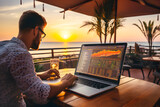 Fototapeta  - Nómada digital de negocios trabajando en la playa junto al mar durante la puesta de sol frente a palmeras. Freelance, trabajo remoto con portátil en vacaciones trading. Empleos del futuro online.