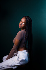 Wall Mural - Portrait of young woman, sitting, with braids, looking at the camera.