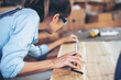 © EKKAPON - Attractive middle aged woman carpenter designer works with ruler, make notches on the tree in workshop. Image of modern femininity. Concept of professionally motivated women