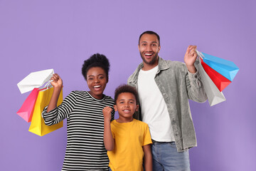 Wall Mural - Family shopping. Happy parents and son with colorful bags on violet background