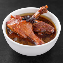 Wall Mural - brown Chinese stewed calf of duck leg with Chinese Star Anise herb on top in white bowl on dark tone texture background, Thai food, Ped Pa Lo, Ped Palo, Ped Palow