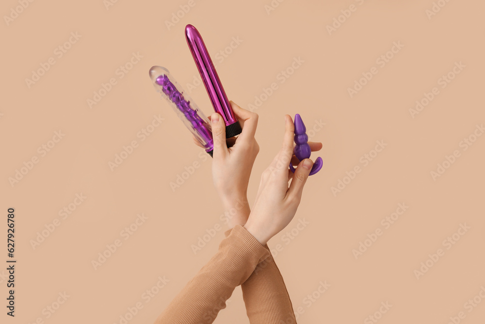 Woman with vibrators on beige background