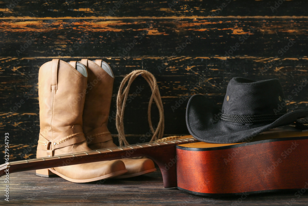 Cowboy hat, guitar and boots on wooden background