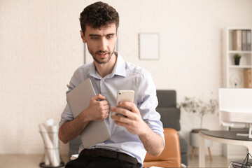 Young businessman working with mobile phone and laptop in office