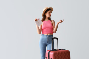 Wall Mural - Young woman with menstrual calendar and suitcase counting on light background