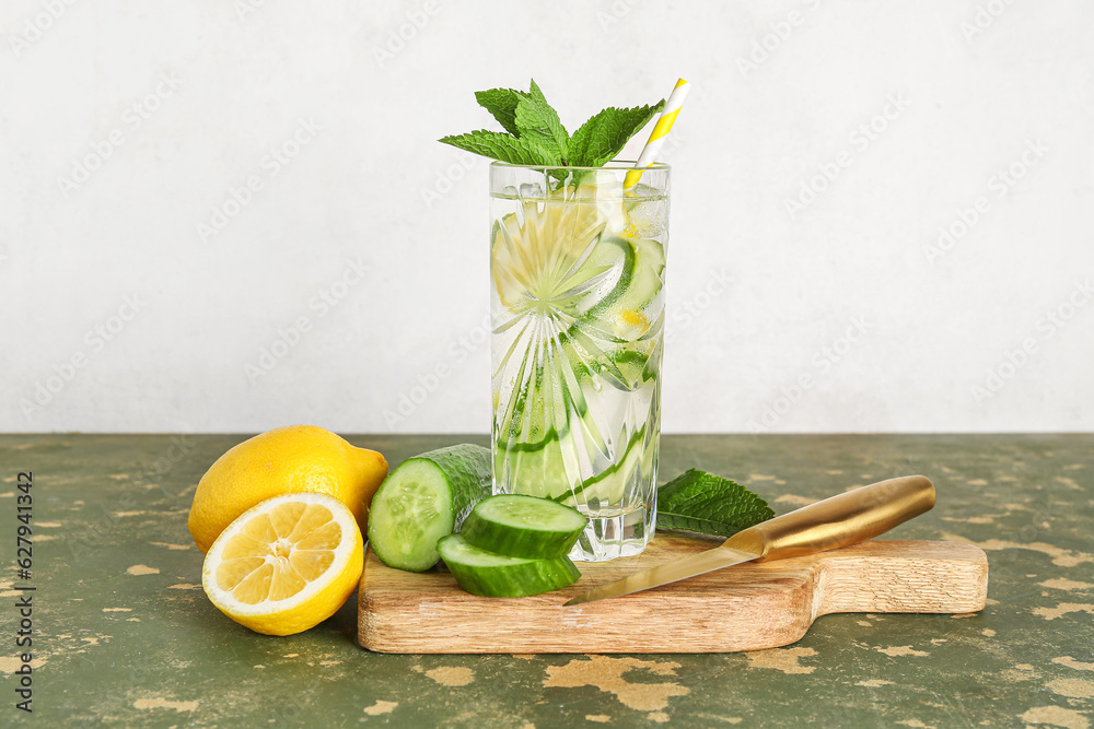 Glass of lemonade with cucumber and mint on green table