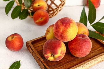 Wall Mural - Wooden board with sweet peaches and leaves on white table