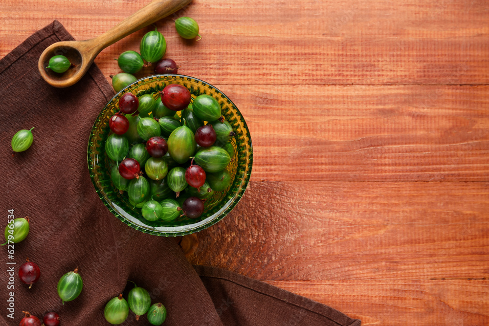 Bowl with fresh gooseberries on wooden background