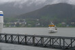 Grey, misty, foggy morning in Juneau Bay, Alaska with small islands channel cruising and houses, glacier mountains and low clouds