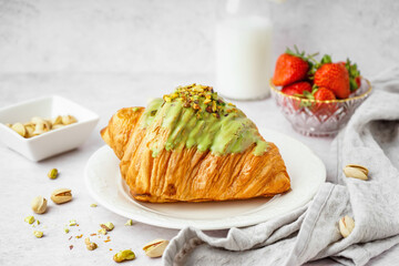 Wall Mural - Plate with sweet croissant and pistachio nuts on white background