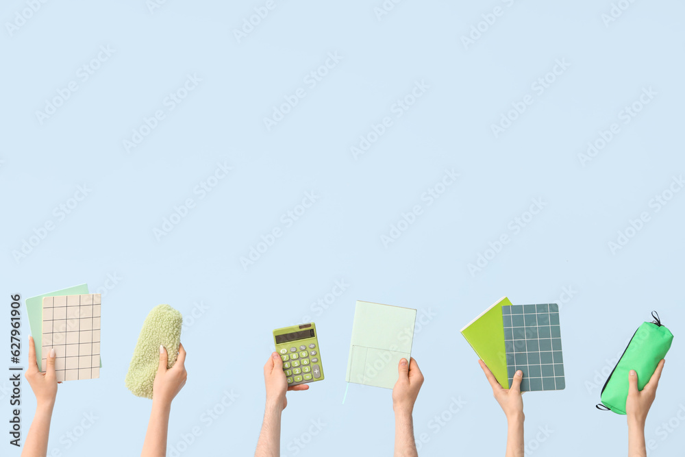Hands with school supplies on blue background