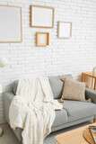 Fototapeta  - Interior of stylish living room with sofa and blank frames on white brick wall