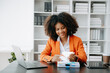 © laddawan - Successful African Businesswoman Analyzing Finance on Tablet and Laptop at modern Office Desk tax, report, accounting, statistics, and analytical research concept..