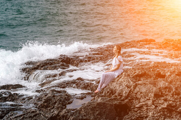 A woman in a storm sits on a stone in the sea. Dressed in a whit