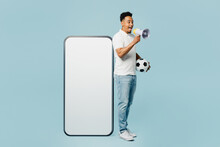 Full Body Young Man Fan In T-shirt Cheer Up Support Football Sport Team Hold Soccer Ball Big Blank Screen Mobile Cell Phone Watch Tv Live Stream Scream In Megaphone Isolated On Plain Blue Background