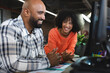 © Wavebreak Media - Happy diverse female and male colleagues sitting at desk using computer and laughing in office