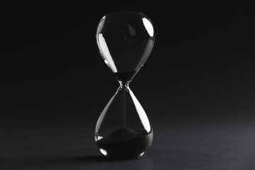 Poster - Close up of hourglass with black sand and copy space on black background
