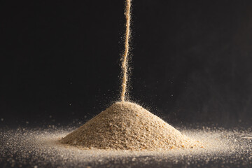 Poster - close up of sand pouring into heap and copy space on black background